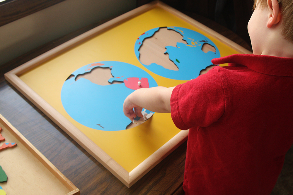 toddler doing montessori continents puzzle